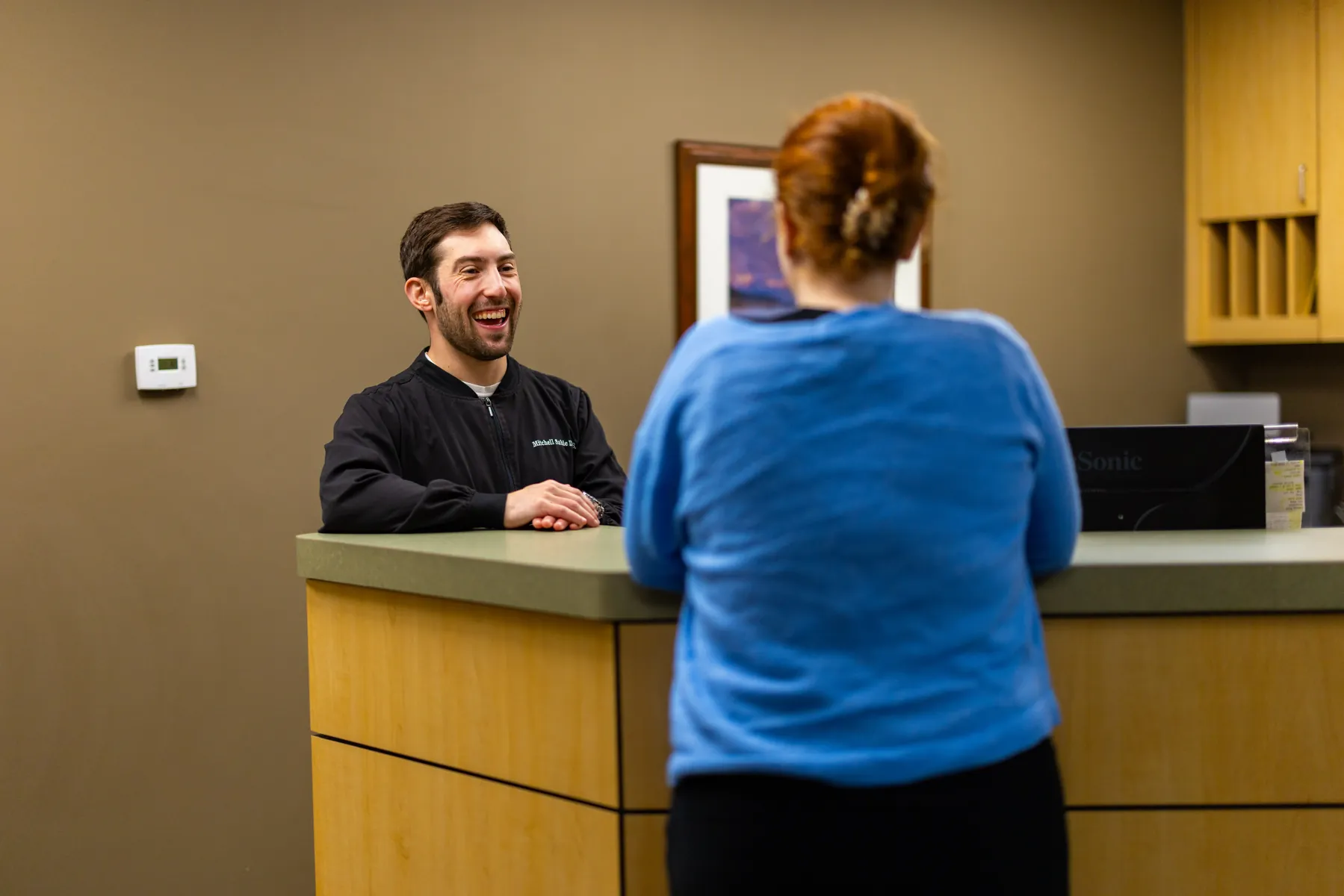 Dr. Mitchell Sable speaking with a patient at the front desk